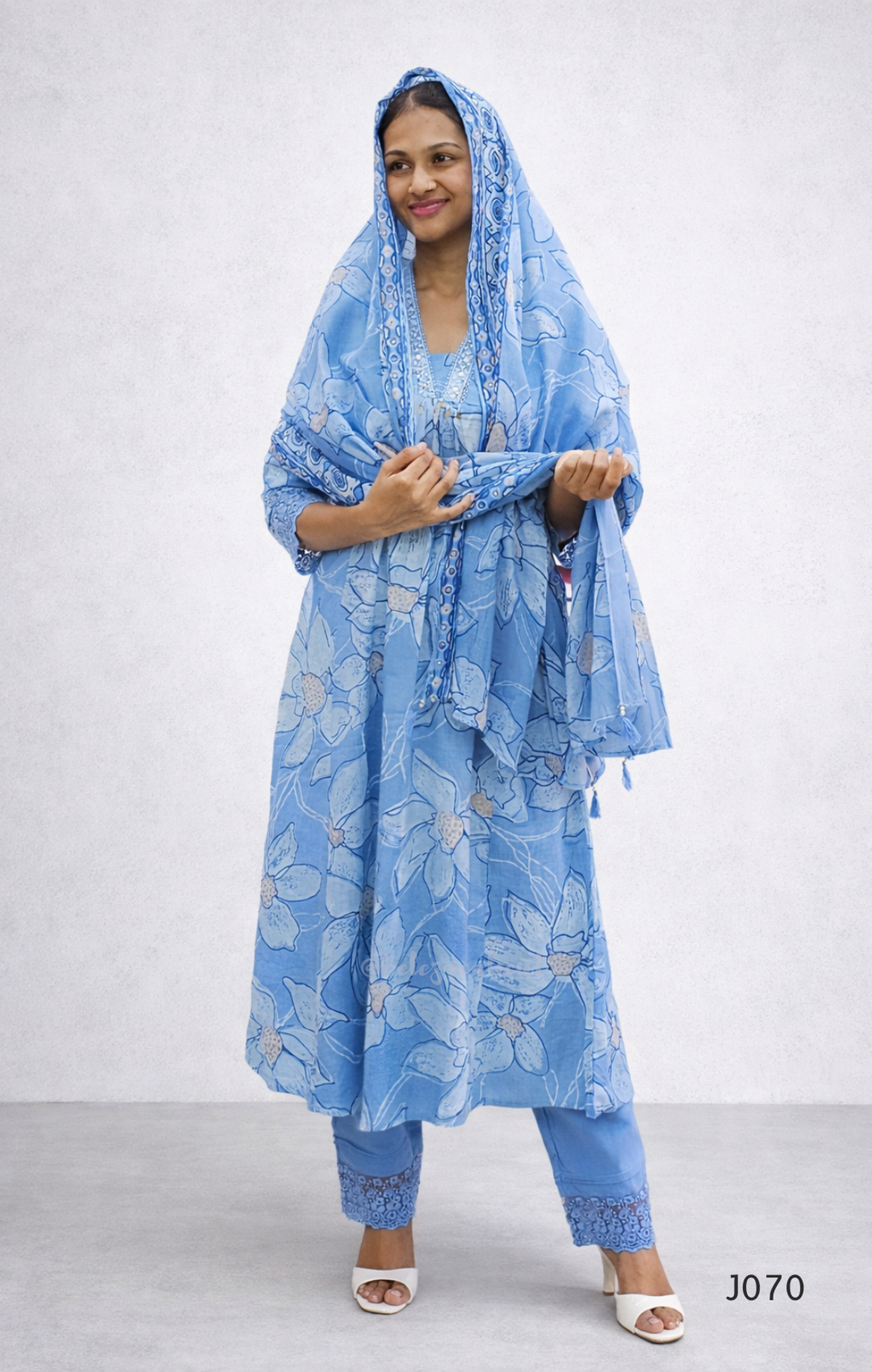 Woman wearing a blue floral outfit with a matching scarf on a white background