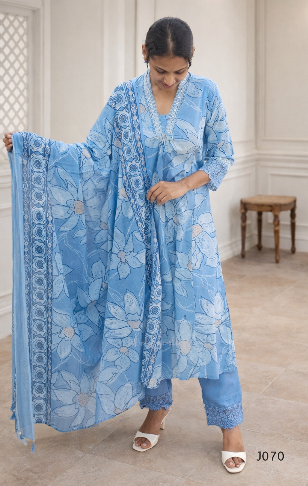 Woman holding a blue floral scarf in a room with a wooden bench.