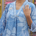 Close-up of a person wearing a blue floral patterned outfit with intricate details.