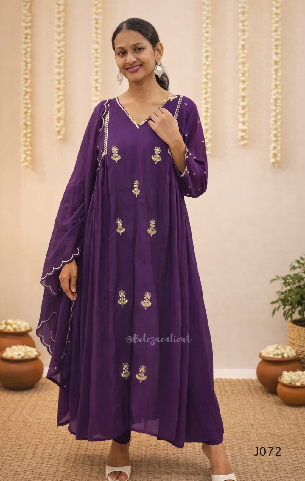 Woman wearing a purple dress with gold embroidery in a decorated indoor setting.