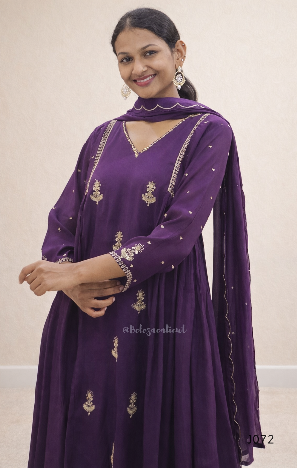 Woman wearing a purple embroidered outfit against a beige background