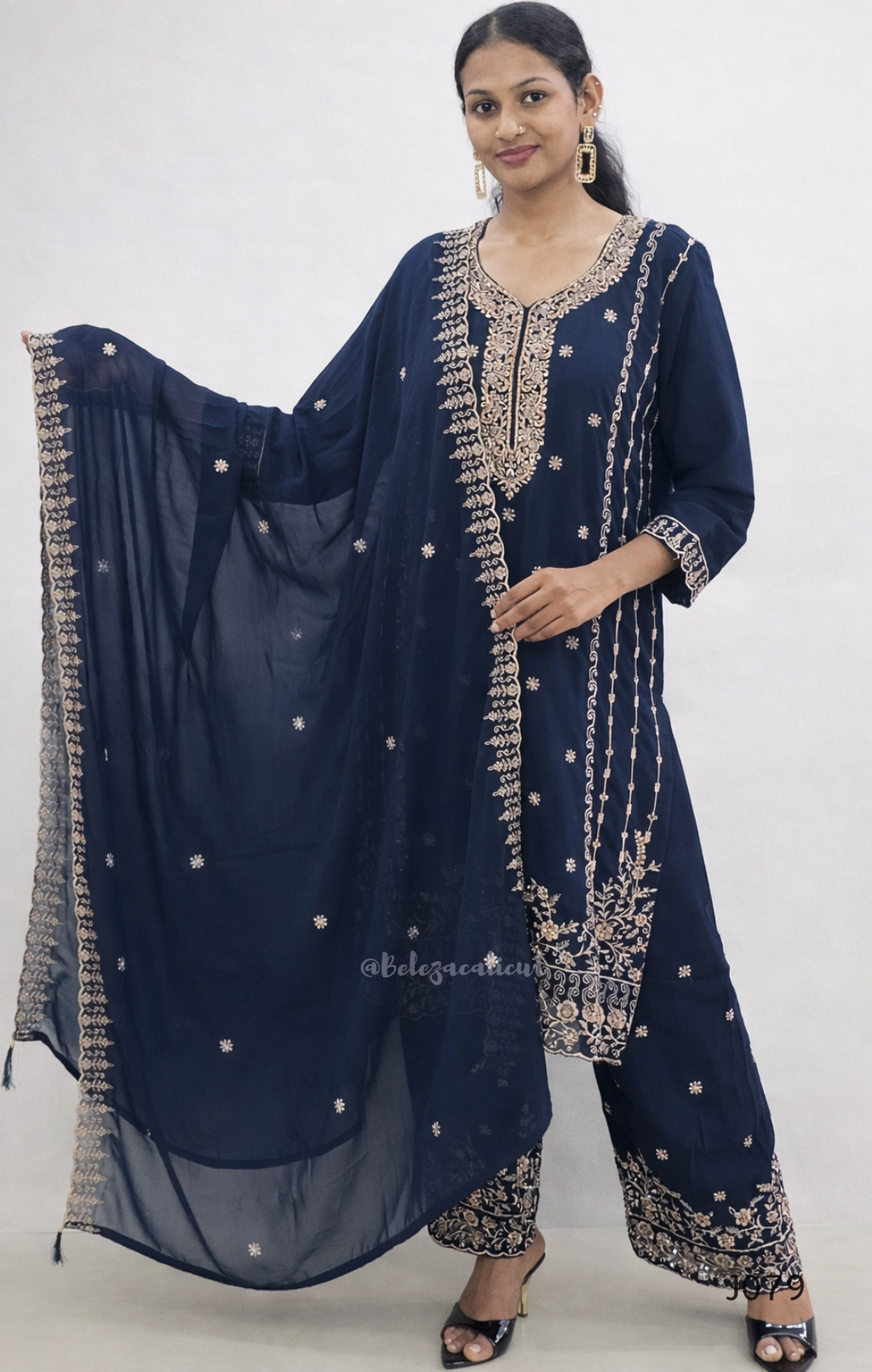 Woman wearing a navy blue traditional outfit with intricate gold embroidery on a white background