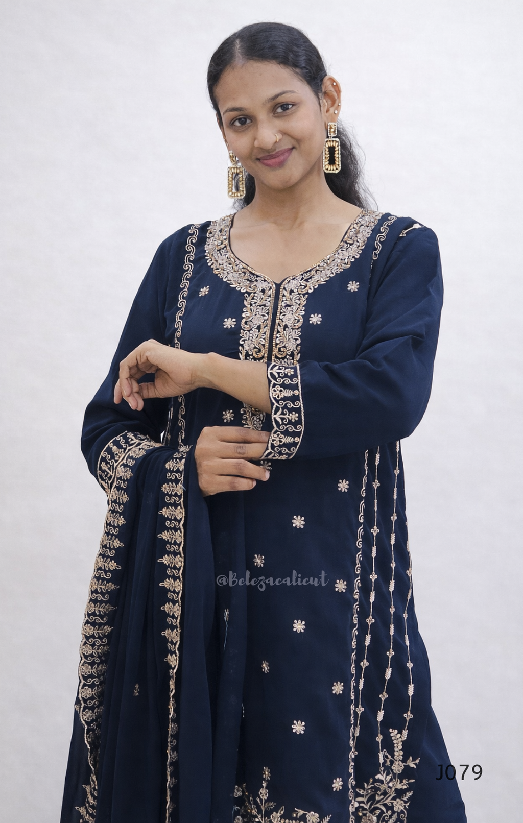 Woman wearing a navy blue traditional outfit with gold embroidery against a white background