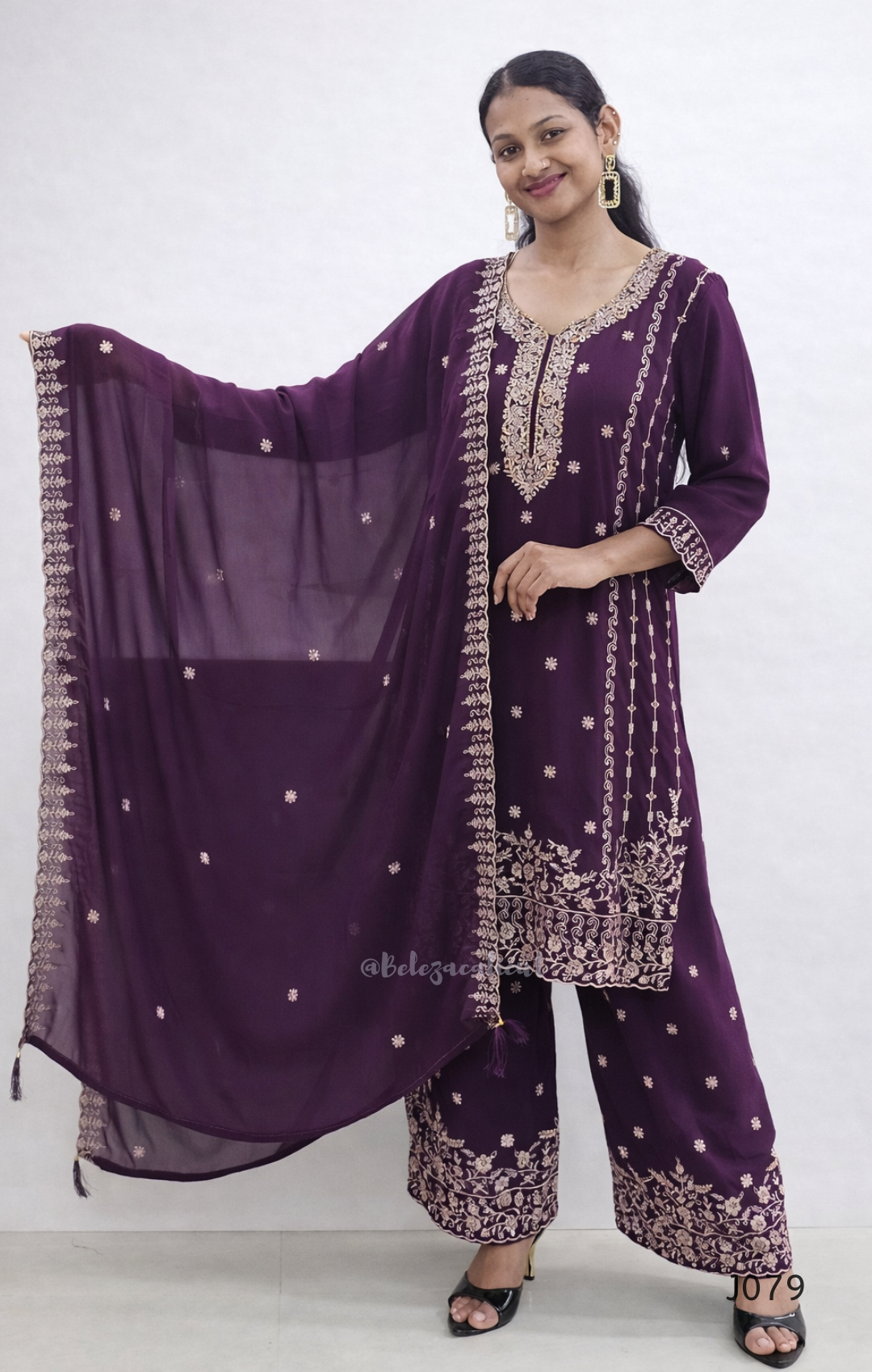 Woman wearing a purple traditional outfit with intricate designs on a white background