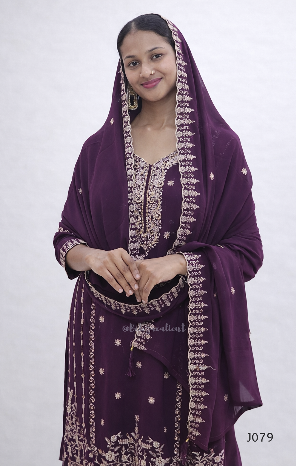 Woman wearing a purple embroidered traditional outfit on a white background