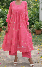 Woman wearing a pink traditional outfit with floral patterns in an outdoor setting.