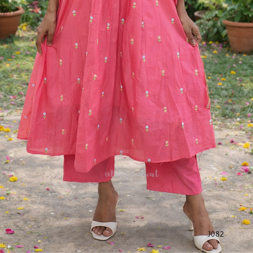 Person wearing a pink traditional outfit with floral patterns on a garden background
