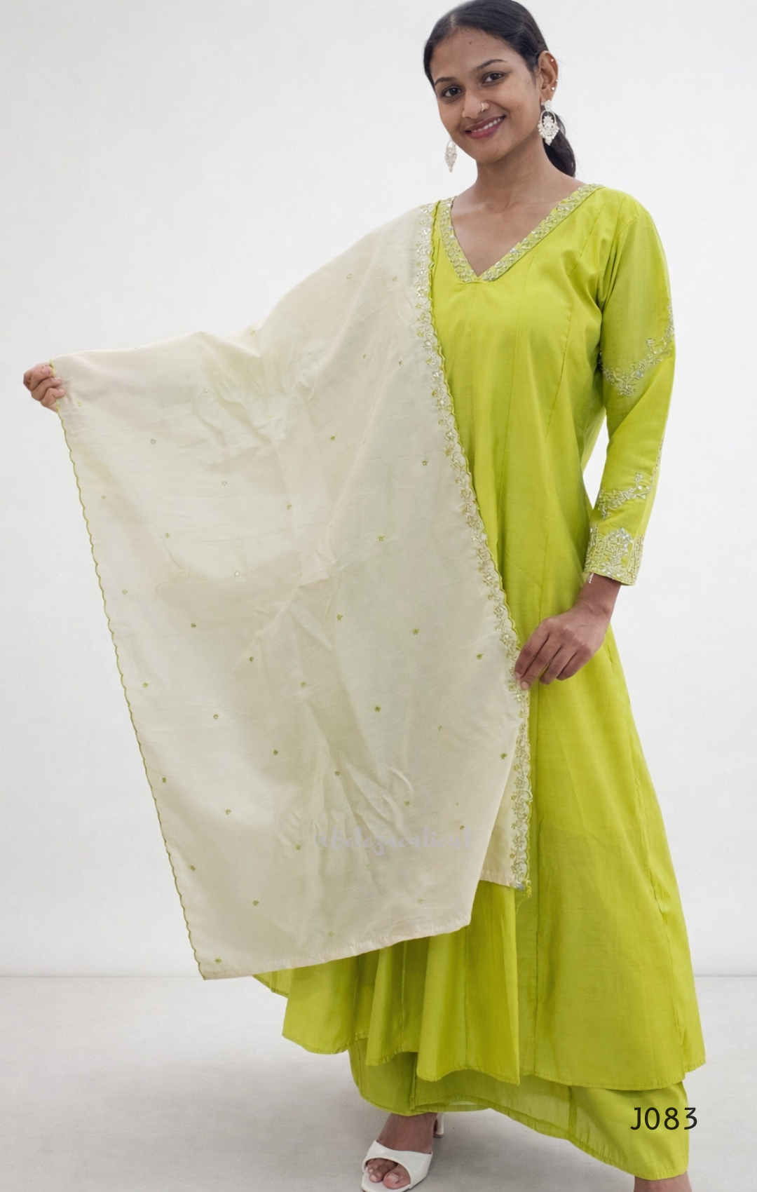 Woman wearing a green traditional outfit with a white dupatta on a white background