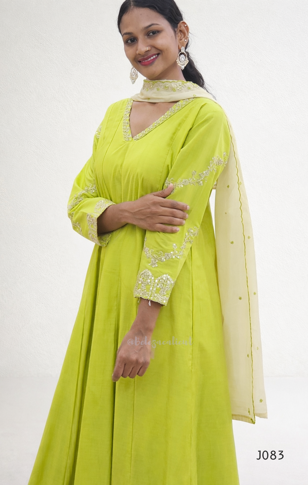 Woman wearing a bright green traditional outfit with white embroidery on a white background