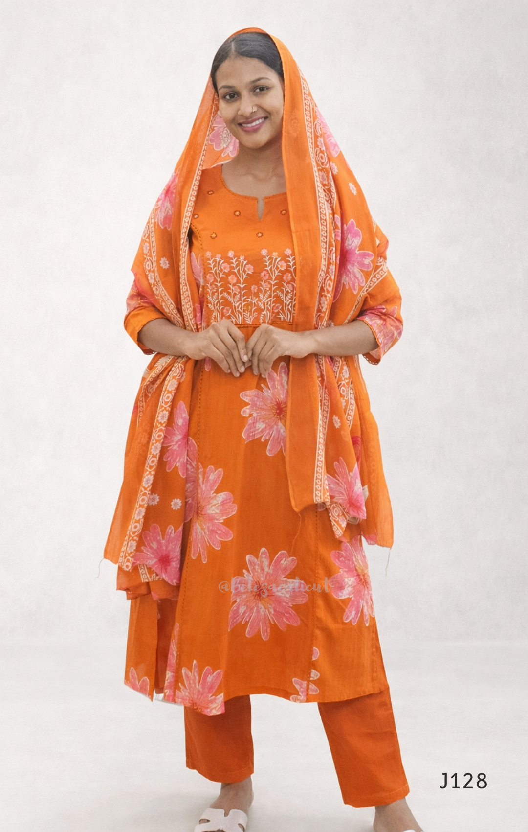 Woman wearing an orange traditional outfit with a floral pattern on a white background