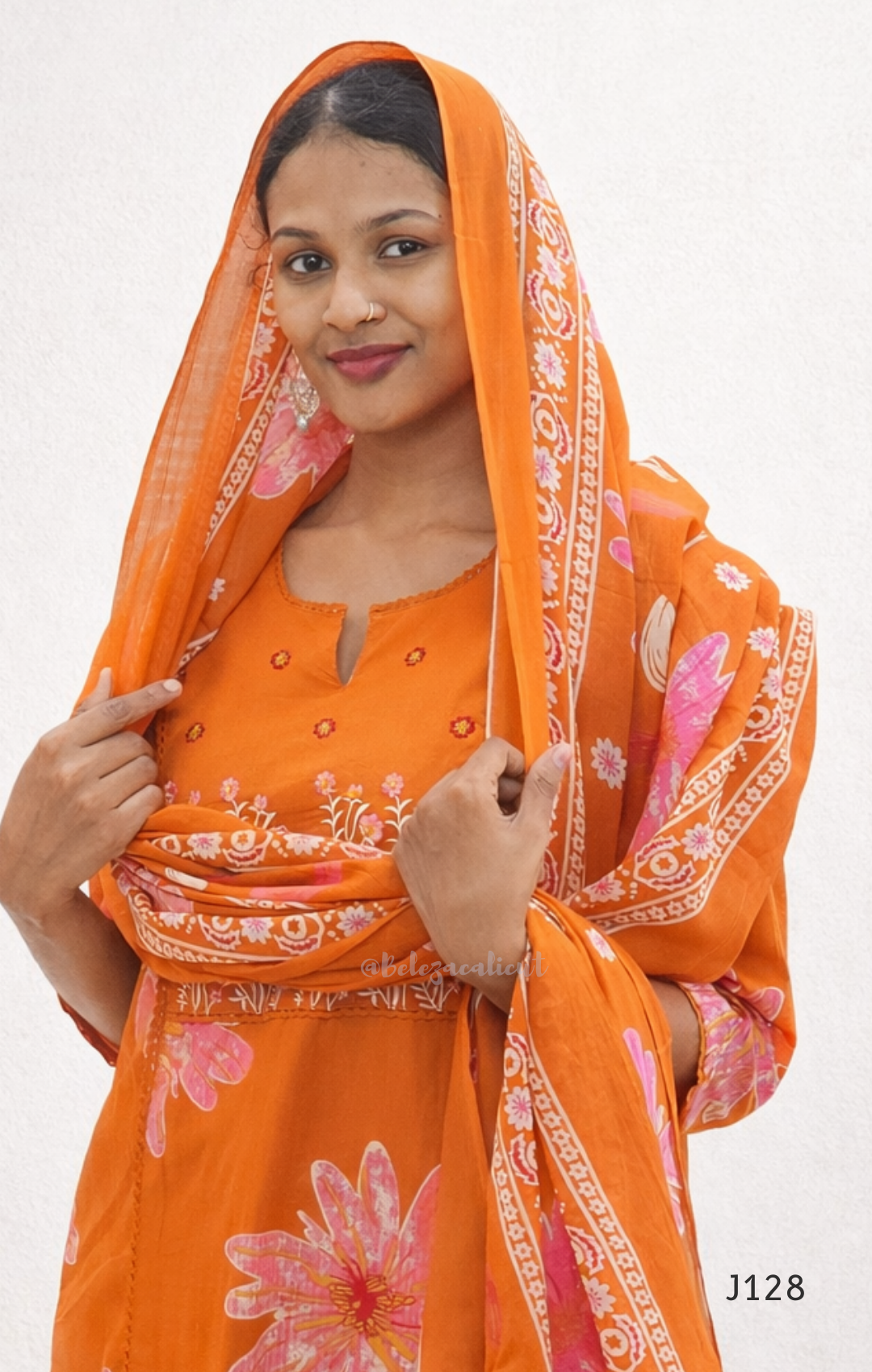 Woman wearing an orange traditional outfit with a matching dupatta on a white background