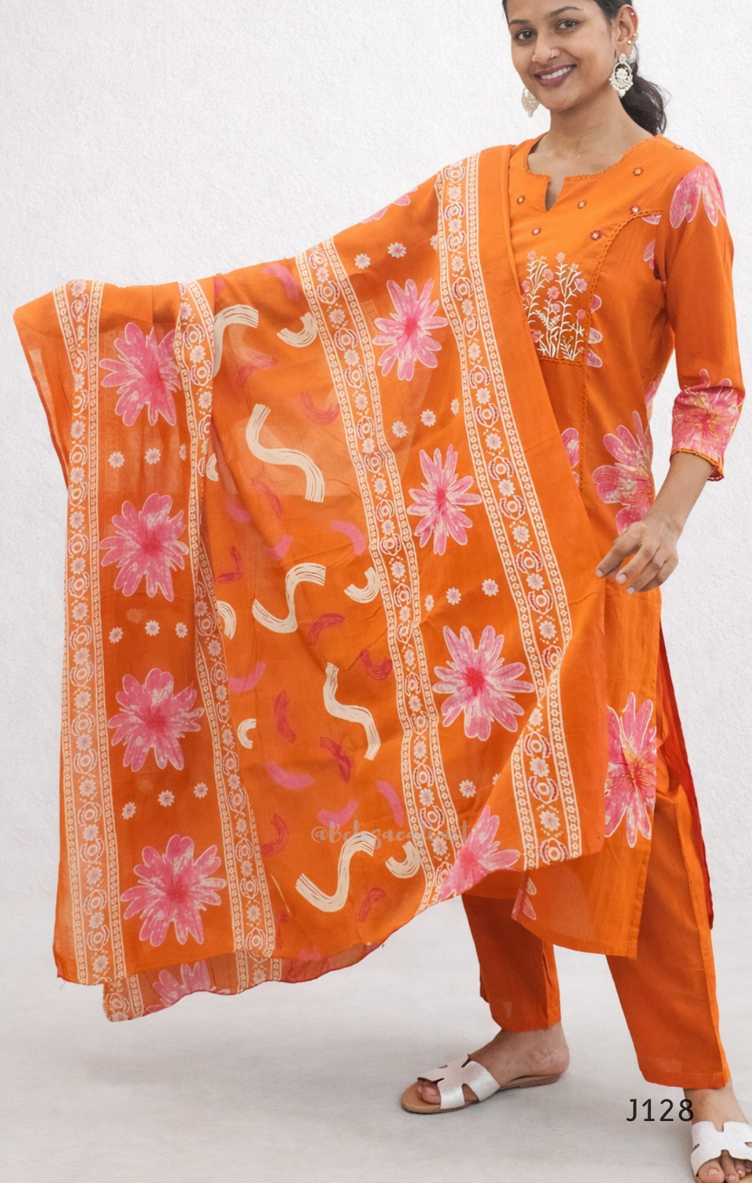 Woman wearing an orange traditional outfit with floral patterns on a white background