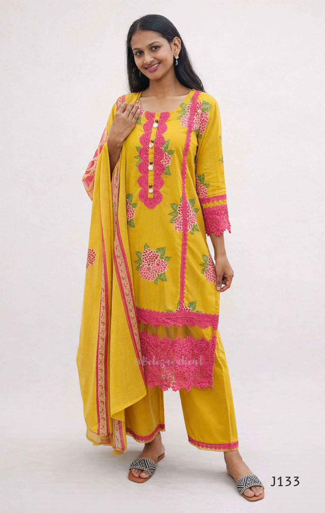 Woman wearing a yellow and pink traditional outfit with floral patterns on a white background