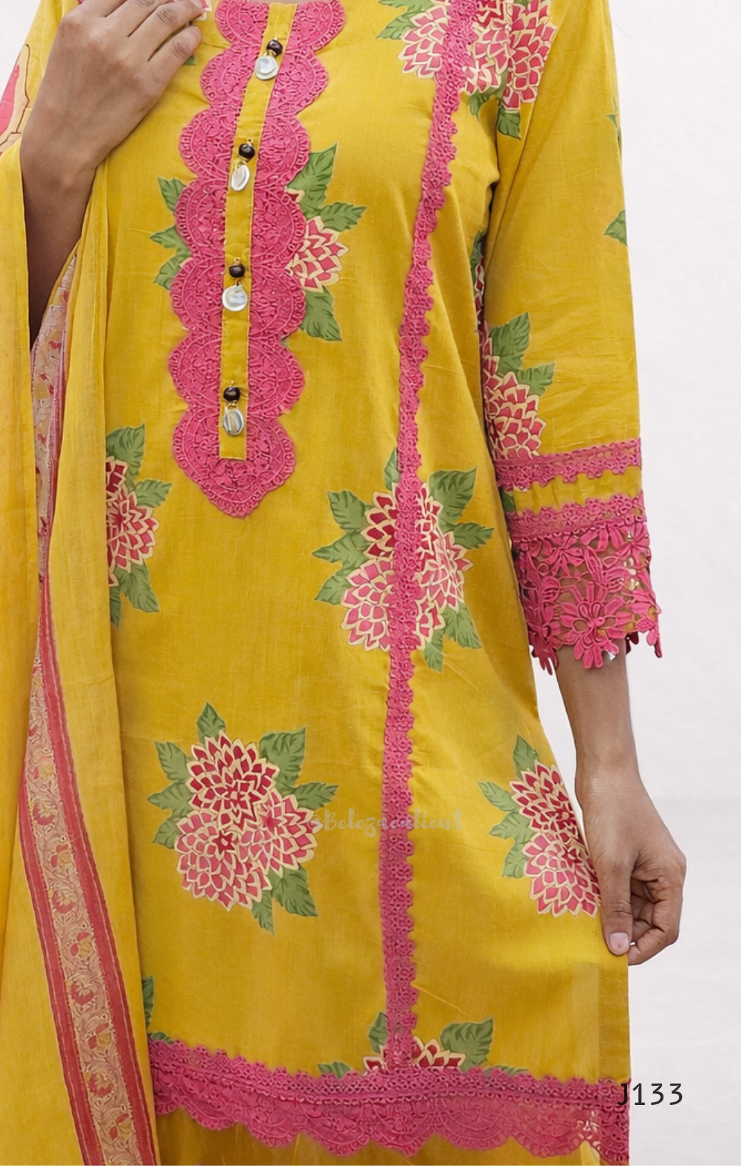 Yellow embroidered dress with pink and green details on a white background
