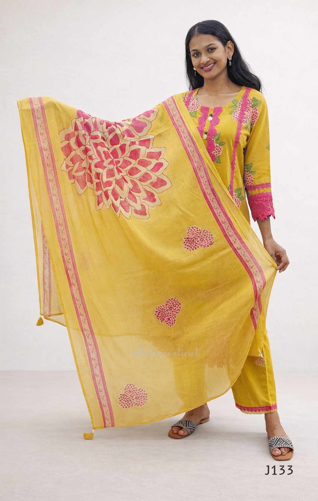 Woman wearing a yellow traditional outfit with pink floral patterns on a white background