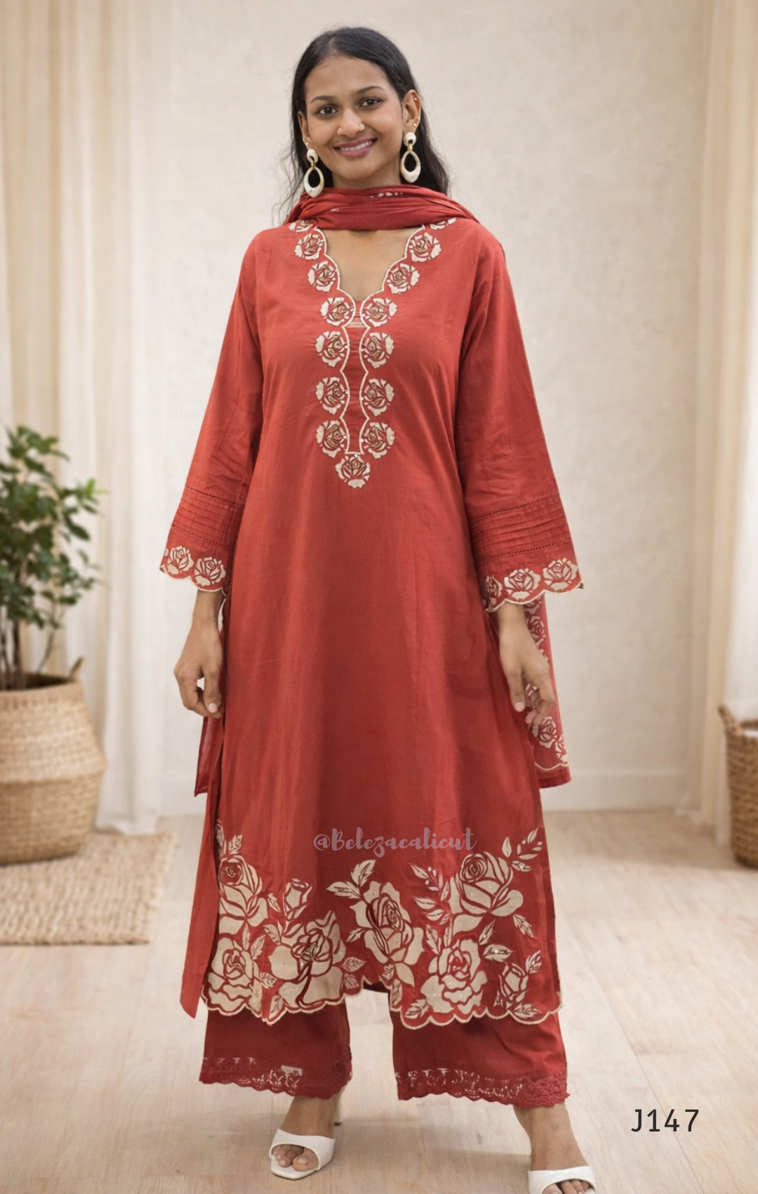 Woman wearing a red embroidered outfit with a plain background