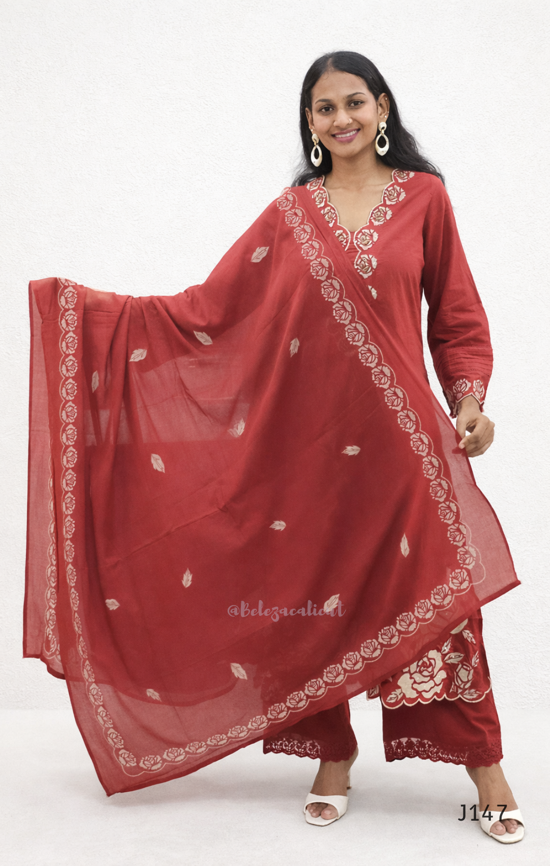 Woman wearing a red traditional outfit with white embroidery on a white background