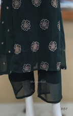 Black dress with silver floral embroidery on a mannequin against a neutral background