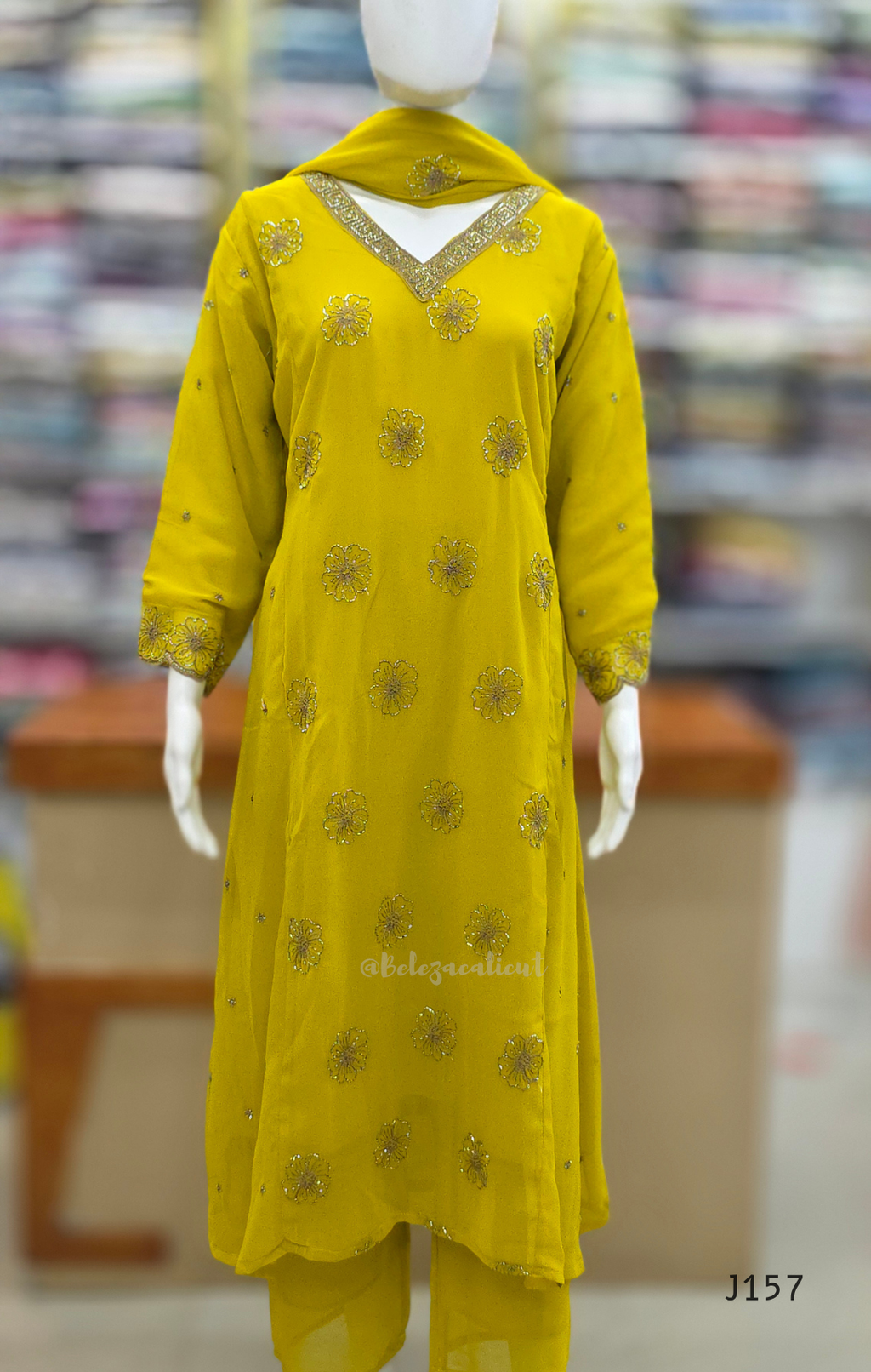 Yellow embroidered outfit on a mannequin with a blurred store background