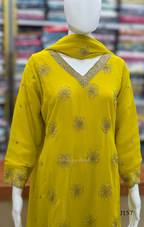 Yellow embroidered dress on a mannequin with a blurred fabric background