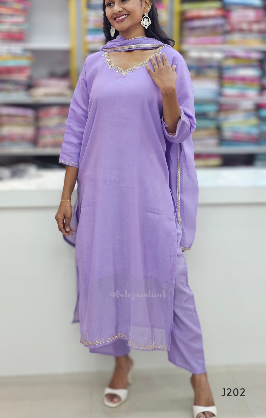 Woman wearing a purple traditional outfit with a matching dupatta in a store setting.