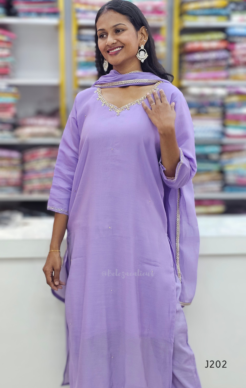 Woman wearing a light purple traditional outfit with a blurred fabric store background