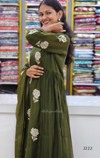 Woman wearing a green embroidered dress in front of fabric rolls
