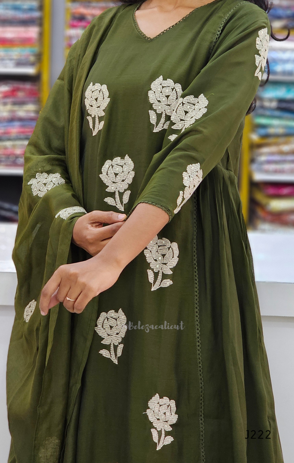Green dress with white floral embroidery in a store setting
