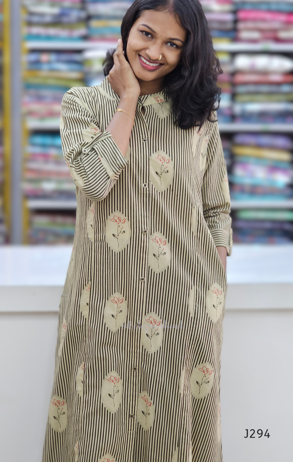 Woman wearing a long, patterned dress with a blurred fabric store background