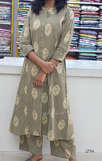 Person wearing a floral and striped outfit with a background of fabric rolls.