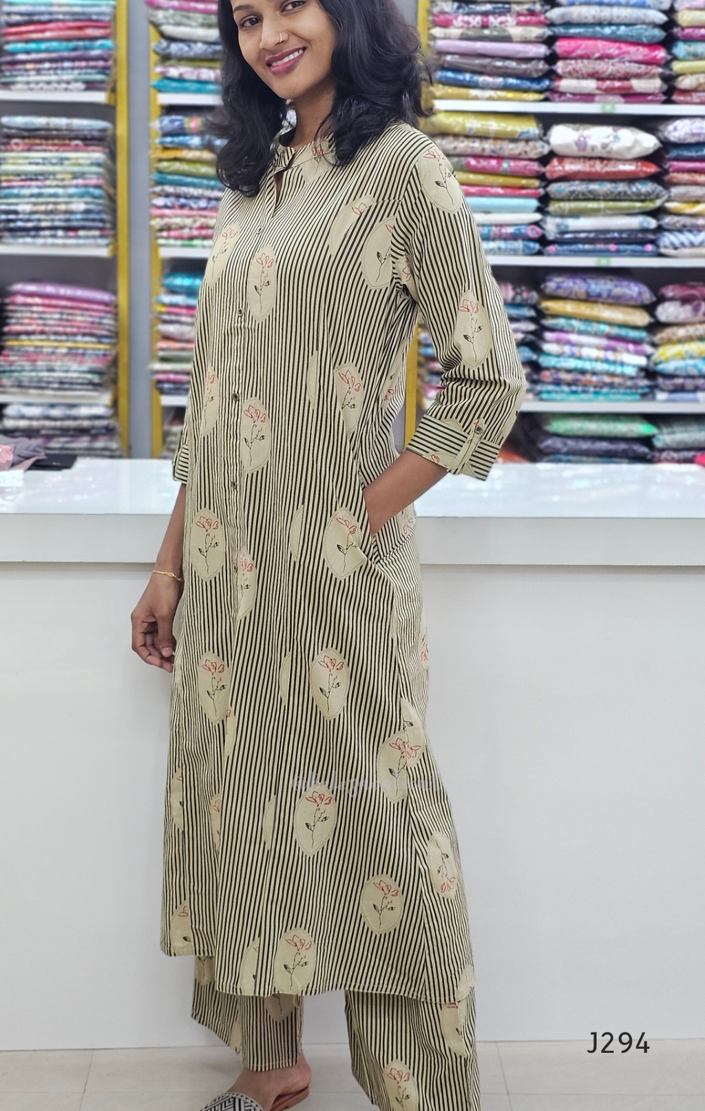 Woman wearing a green and white patterned kurta with pants in a fabric store.