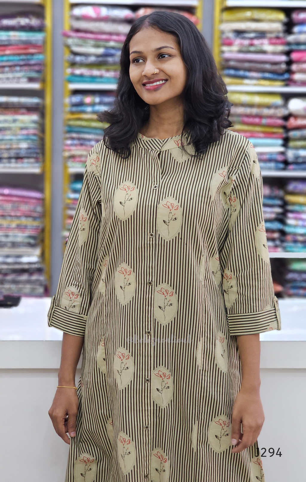 Woman wearing a floral-patterned kurta in front of fabric shelves