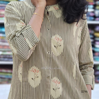 Person wearing a striped shirt with floral patches in a blurred indoor setting