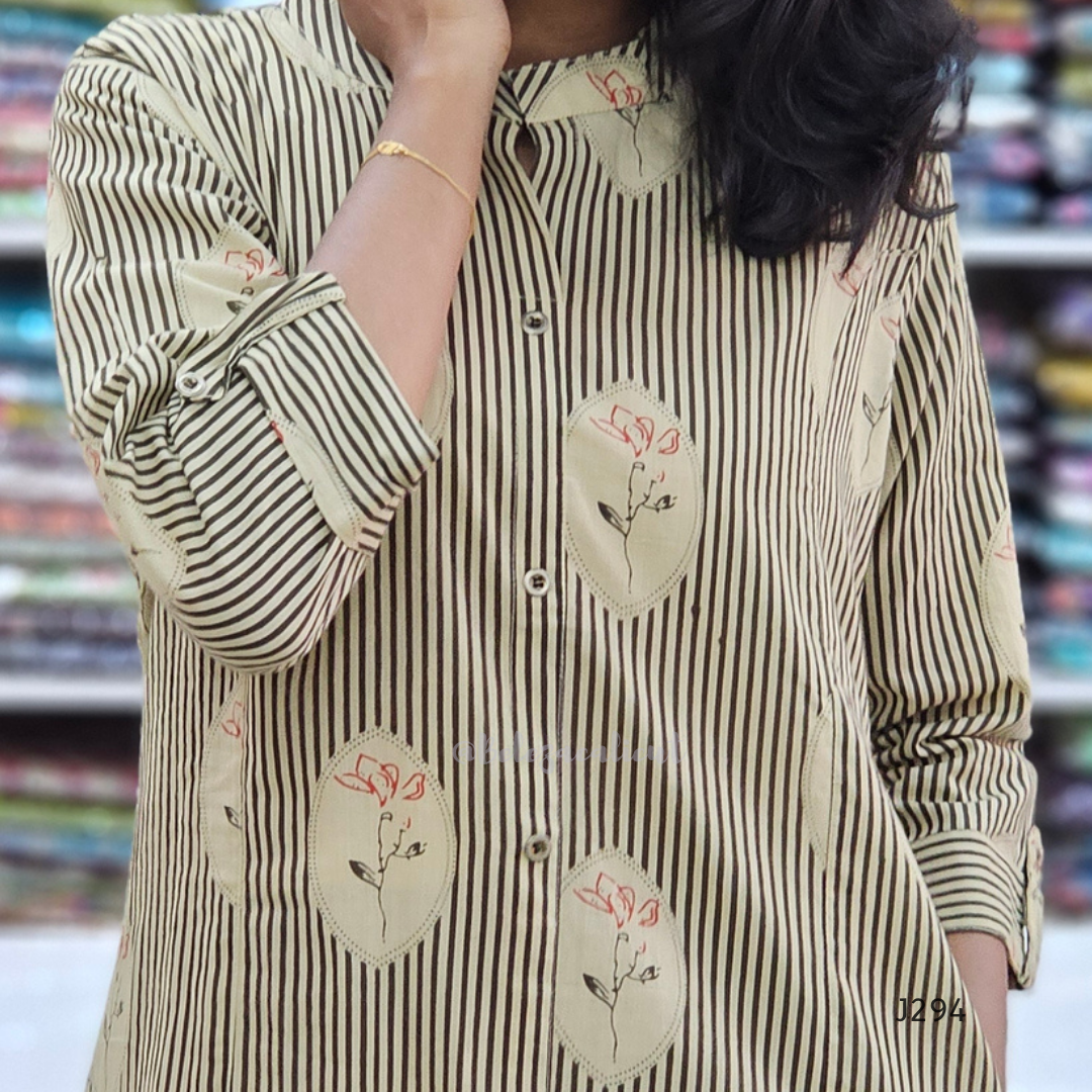 Person wearing a striped shirt with floral patches in a blurred indoor setting