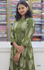 Woman wearing a green patterned kurta with a colorful bookshelf background