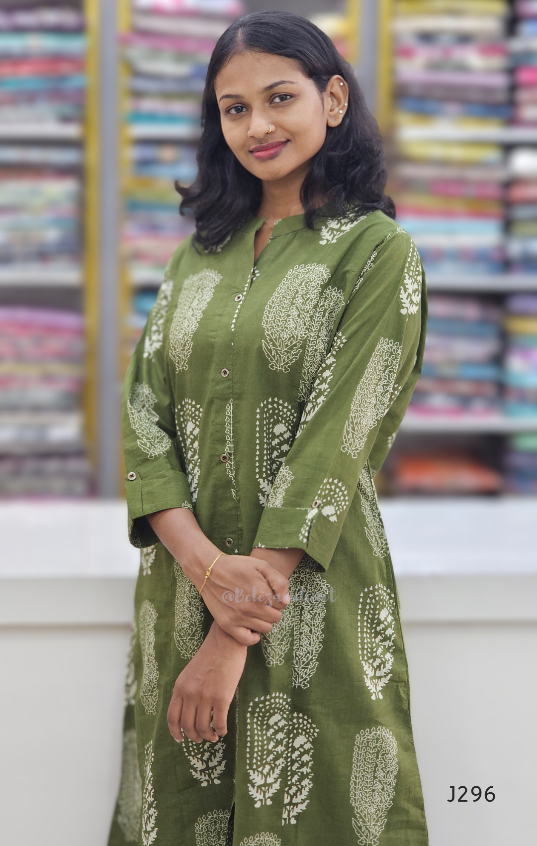 Woman wearing a green patterned kurta with a colorful bookshelf background