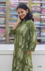 Woman wearing a green patterned dress in front of a bookshelf.