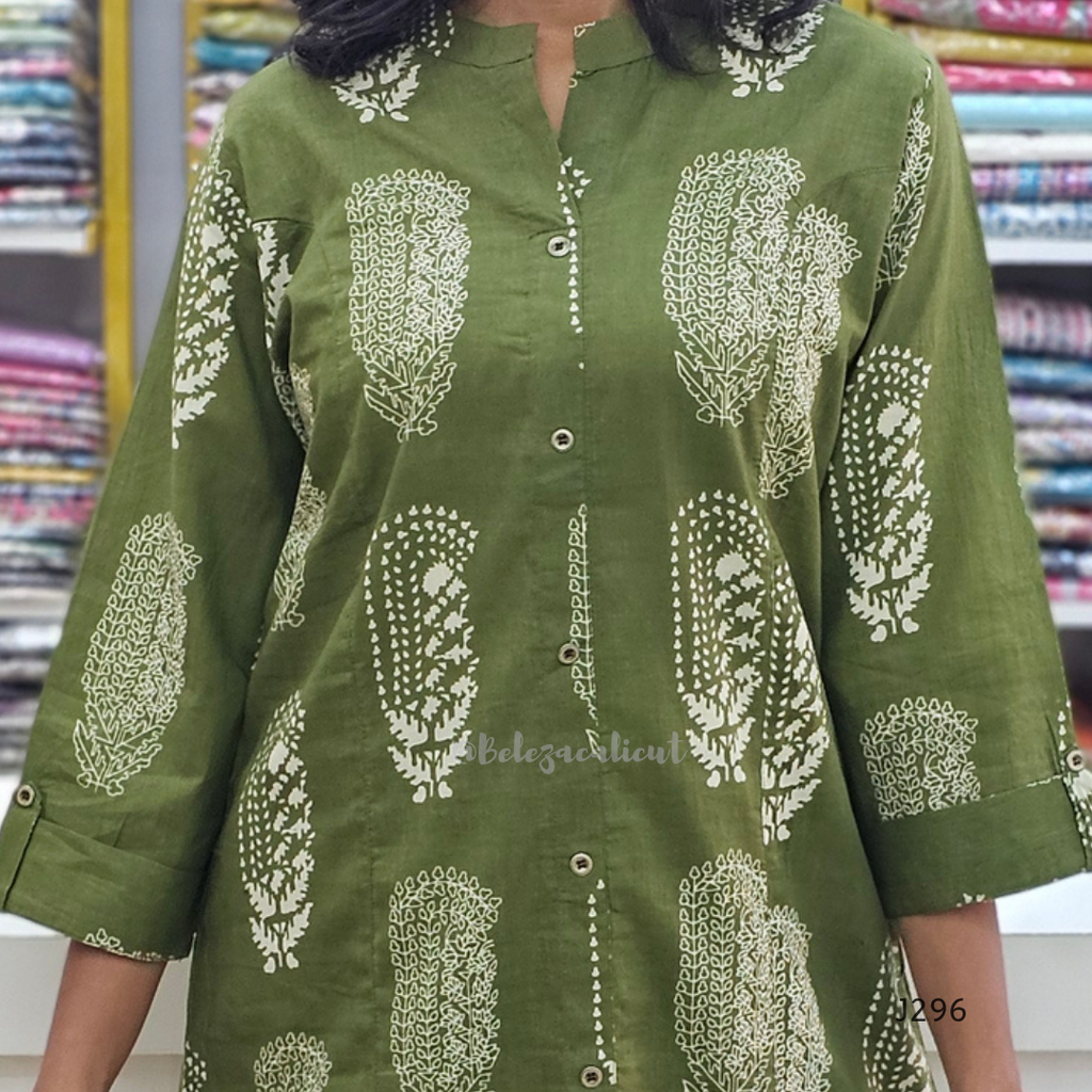 Green kurta with white floral patterns worn by a person, with a fabric store background.