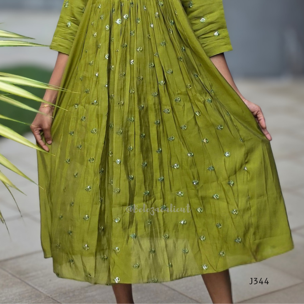 Green dress with floral patterns held by a person, blurred background