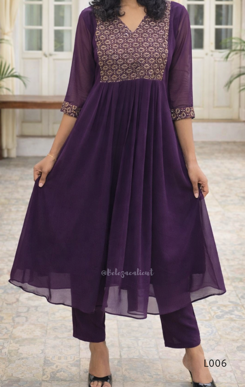 Woman wearing a purple outfit with a patterned top in an indoor setting
