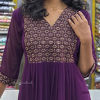 Purple dress with intricate patterned top in a store setting