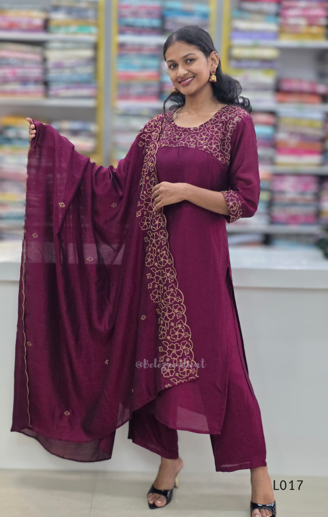 Woman in a maroon traditional outfit with a matching dupatta in a store setting