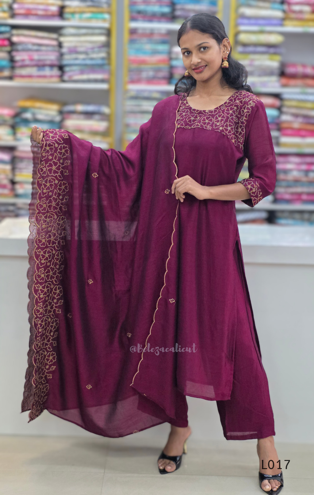 Woman wearing a maroon traditional outfit with a dupatta in a store setting