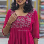 Woman wearing a pink dress with white embroidery in a store setting