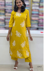 Woman wearing a yellow kurta with white floral patterns in a store setting.