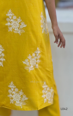 Yellow outfit with white floral embroidery on a plain background
