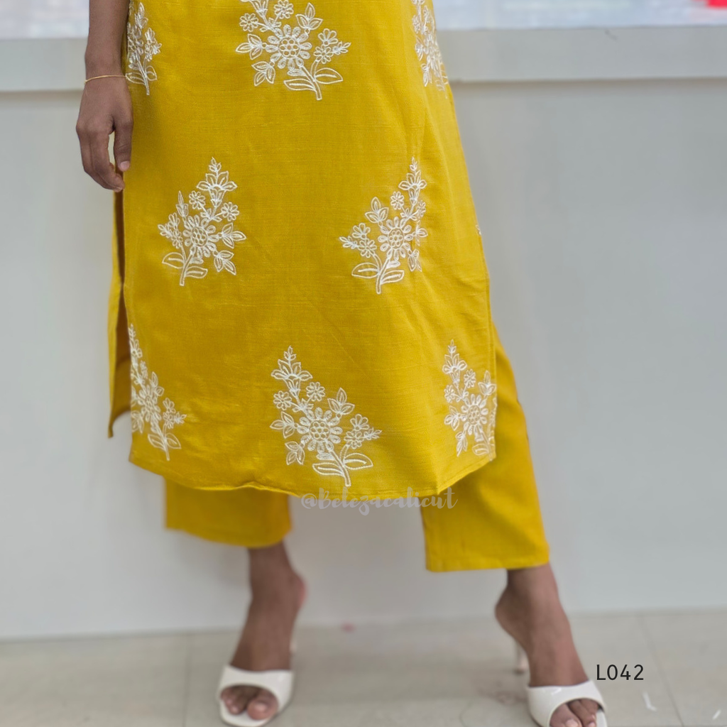 Yellow dress with white floral patterns worn by a person on a plain background