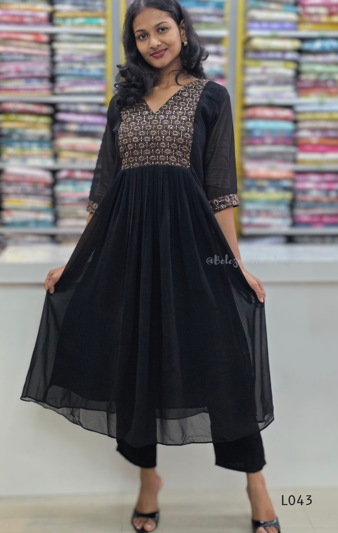Woman wearing a black dress with floral patterns in a fabric store.