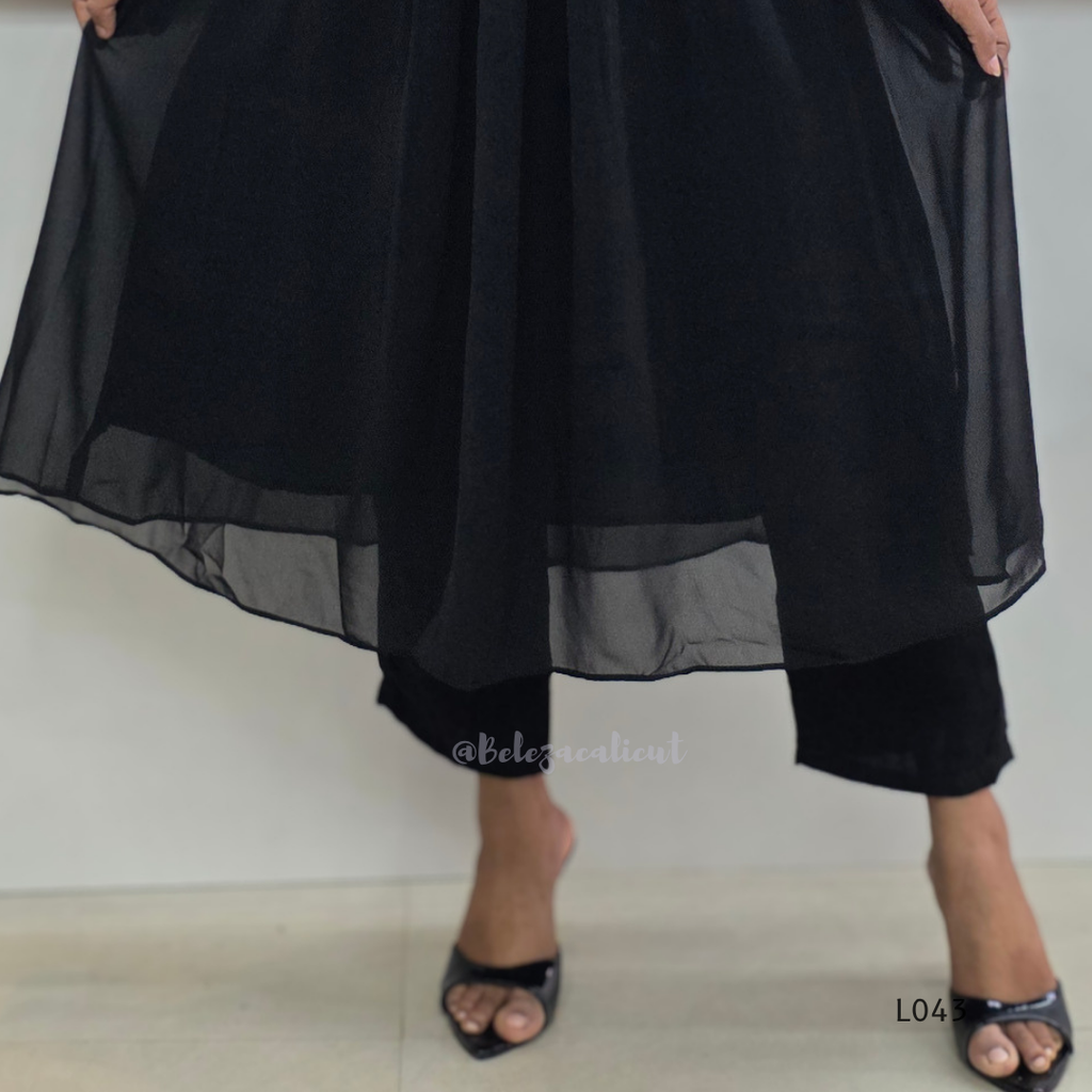Black outfit with sheer overlay on a plain background