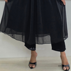 Black outfit with sheer overlay on a plain background